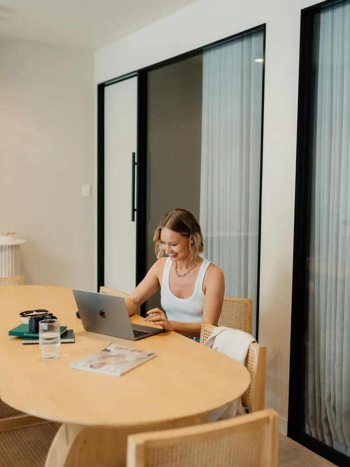 Tamsyn smiling at her laptop at the studio table